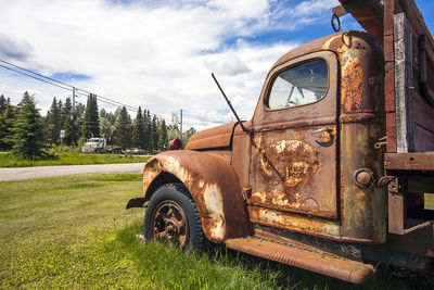 Abandoned car on field against sky