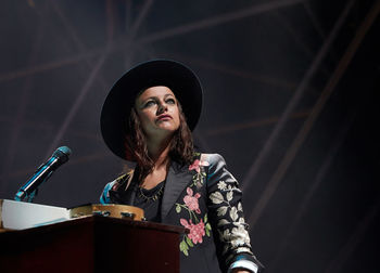 Young woman wearing hat standing at music concert