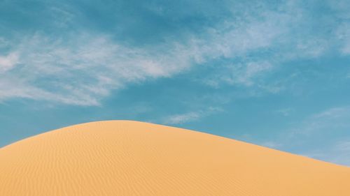 Low angle view of sand dunes against sky