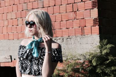 Young woman wearing sunglasses against wall