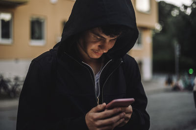 Teenage boy text messaging through smart phone