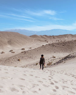Rear view of man walking on desert against sky
