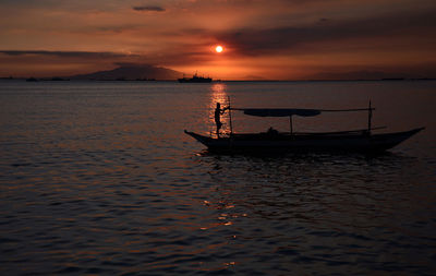 Silhouette sailboat in sea against sky during sunset