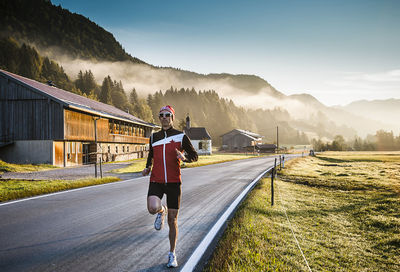 Full length of man jogging on road by field at morning