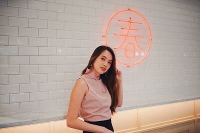 Portrait of smiling young woman standing against wall