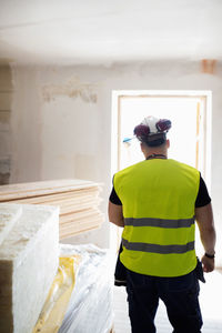 Rear view of man standing in brightly lit room at construction site