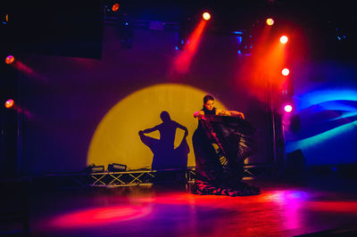 Full length of woman standing against illuminated lights at night