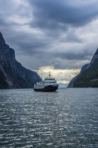 Scenic view of fjord and ferry against sky