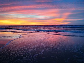 Scenic view of sea against dramatic sky during sunset