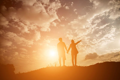 Silhouette friends standing against sky during sunset