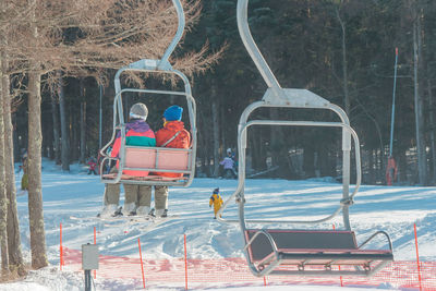 Rear view of people sitting on snow covered field