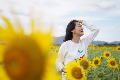 Portrait of young woman standing against yellow flower