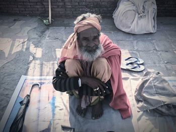 High angle portrait of senior man sitting on street