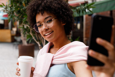 Smiling young woman with afro hairstyle taking selfie