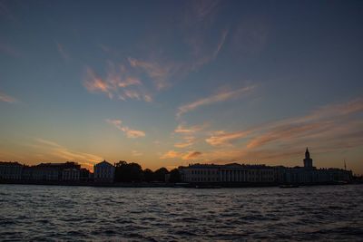 Scenic view of sea and buildings against sky at sunset