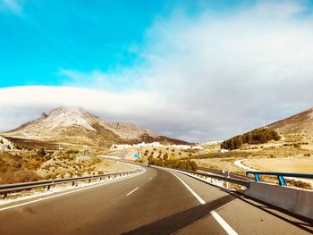 Road leading towards mountains against sky