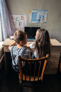 Group of schoolkids or friends wearing headphones sitting near laptop at home. family, school pupil