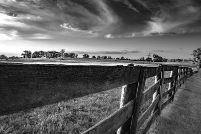 Weathered wooden rail fence seen at vanishing perspective in a lush bluegrass horse pasture.