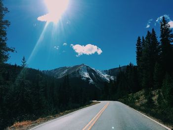 Road amidst trees against blue sky