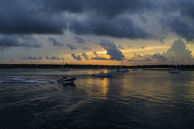 Sailboats in sea against dramatic sky