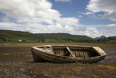 Abandoned boat on land against sky