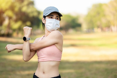 Beautiful woman wearing mask exercising at park