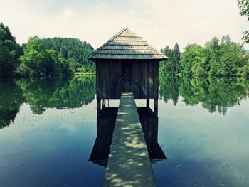 Wooden post in lake against sky