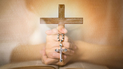 Human hand holding cross on wood