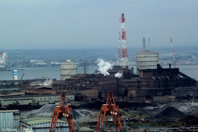 Factory by sea against sky