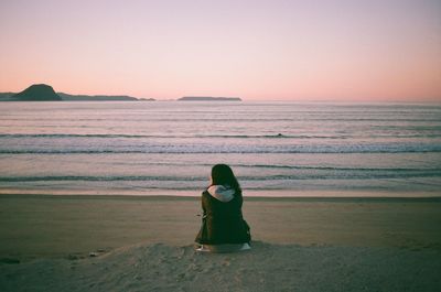 Rear view of woman on beach against sky during sunset