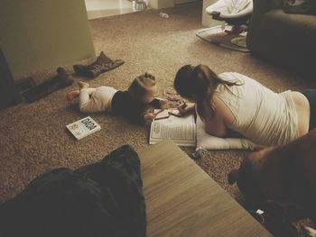 Mother and daughter coloring book while lying on floor at home