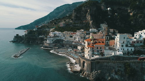 Aerial view of town by sea against sky