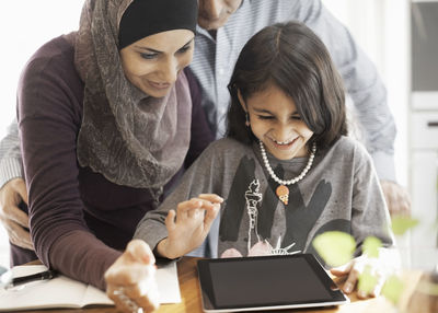 Muslim couple with daughter using digital tablet at home