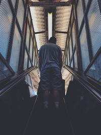 Rear view of man walking on escalator