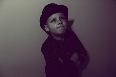 Boy in hat looking up against wall