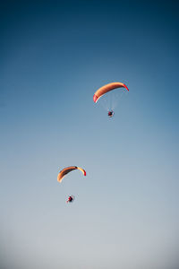 Low angle view of person paragliding against clear sky