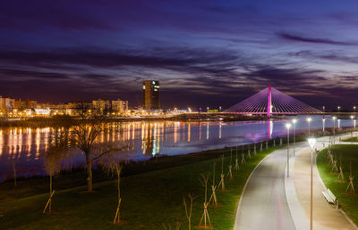 Illuminated bridge over river at night