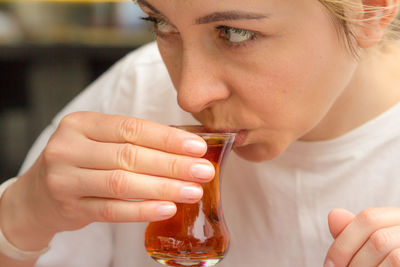 Close-up of woman looking away while drinking at home