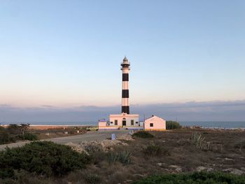 Lighthouse amidst buildings against sky