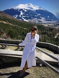 Woman standing by railing against mountains