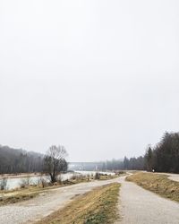 Road amidst field against clear sky during winter