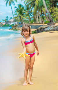 Young woman wearing bikini while sitting on beach