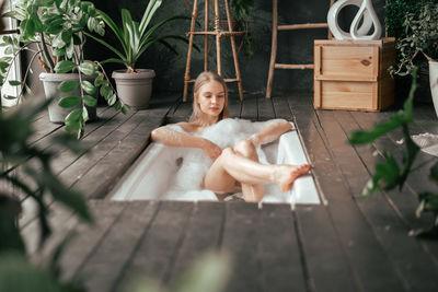 Young beautiful woman taking bath with bubbles and enjoing wellness and wellbeing process