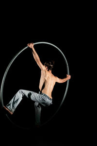 Midsection of shirtless man making face against black background