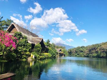 Scenic view of lake amidst trees and houses against sky