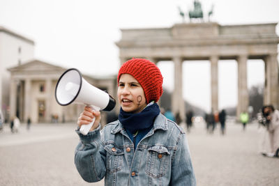 Teenage girl with a woman symbol painted on her face with a megaphone in her hand at a demonstration