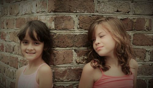 Portrait of happy girl standing against brick wall