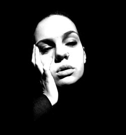 Portrait of young woman against black background