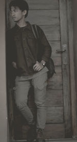 Full length of young man standing against door