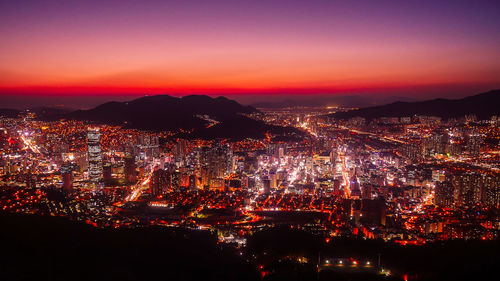 Illuminated cityscape against sky at night